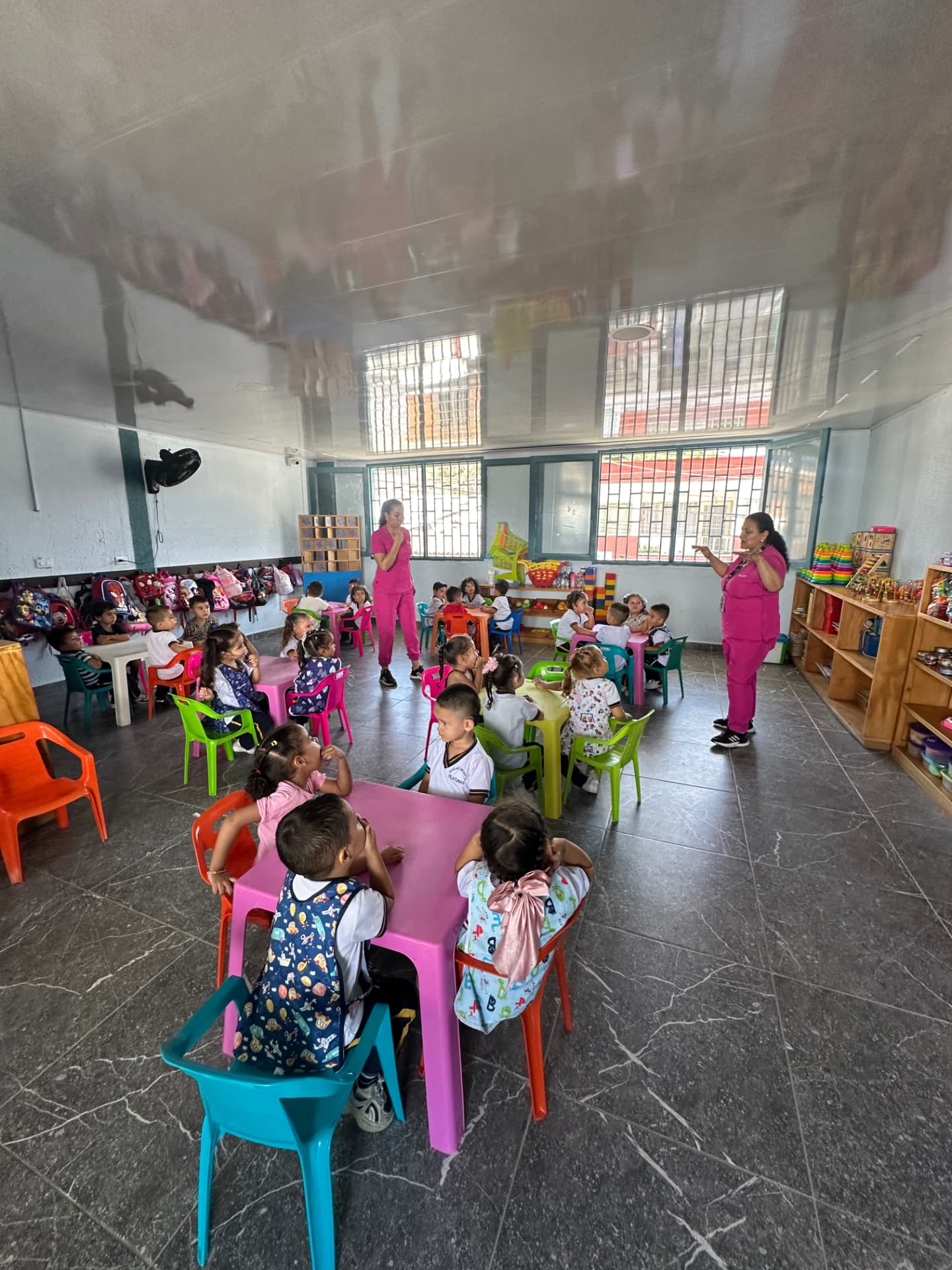 Aula amplia del Hogar Infantil Pilatunas con niñas y niños en mesas de colores